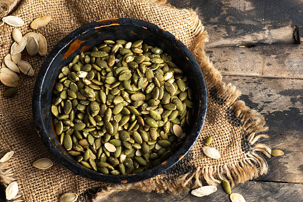 Organic Green Pumpkin Seeds in Black Bowl on Rustic Table