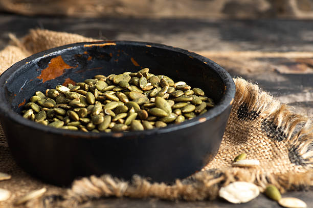 istock Organic Green Pumpkin Seeds in Black Bowl on Rustic Table 2218389191