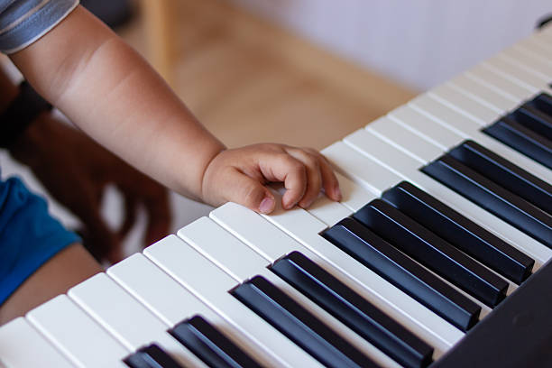 Baby's hand exploring music, touching the keys of a piano keyboard
