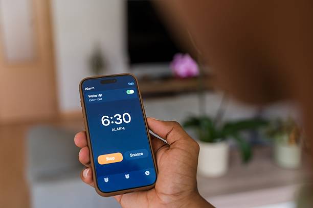 istock Person stopping alarm clock on smartphone 2218391543