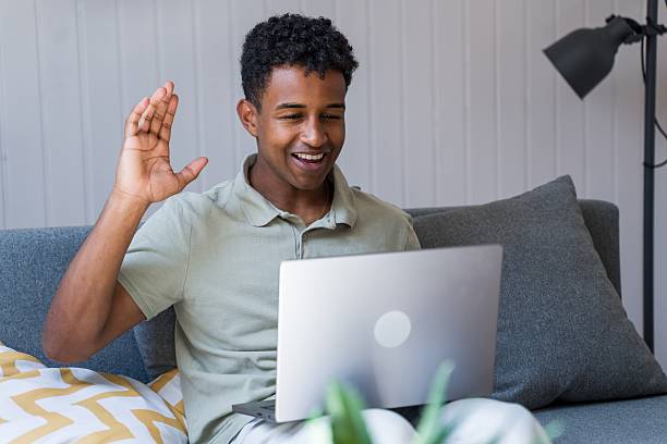 istock man waving at someone during a video call 2218392207