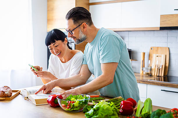 istock Couple Looking Up Recipe While Preparing Fresh Meal in Kitchen 2218392583