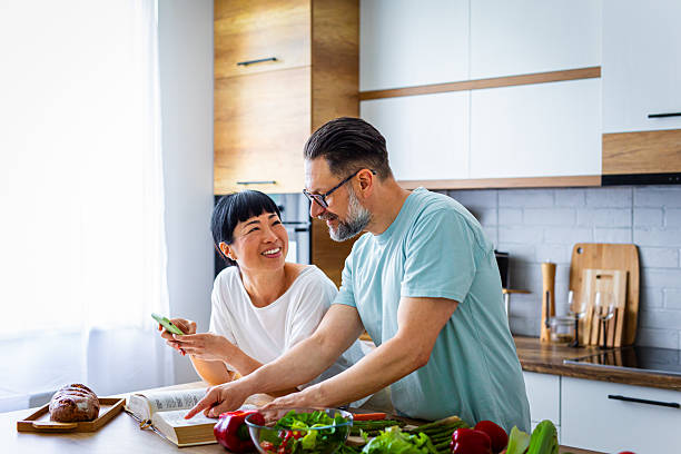 istock Couple Looking Up Recipe While Preparing Fresh Meal in Kitchen 2218393104