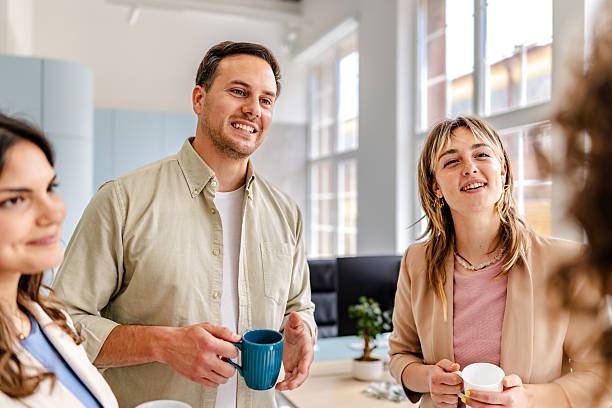 istock Coworkers enjoy a casual conversation in a modern office setting while holding coffee mugs during a productive workday 2218404961