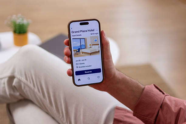 istock Tourist booking hotel room online using smartphone app while relaxing on sofa 2218405111