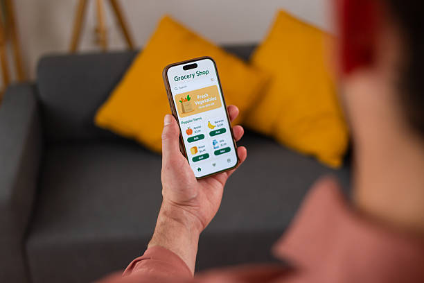 istock Man using grocery shopping app on smartphone at home 2218405211