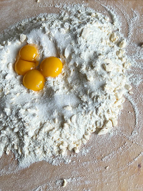 istock Eggs, flour, sugar and other dough ingredients lying on the board before mixing 2218405290