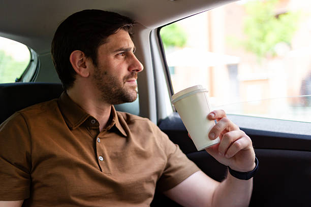 istock Businessman drinking coffee while looking out car window 2218405654
