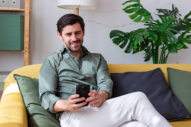 istock Young man relaxing on sofa using smartphone at home 2218406001