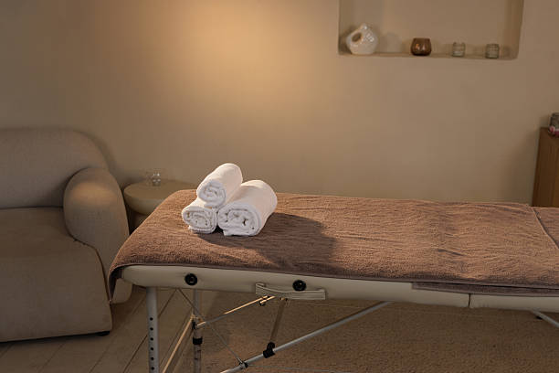 istock Minimalist spa interior with a clean massage table topped with neatly rolled white towels in a calming environment ready for a wellness treatment session. 2218406717