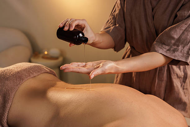 istock Spa therapist pours warm massage oil into hands before applying it to a client's back during a professional relaxation session in a tranquil wellness center. 2218406789