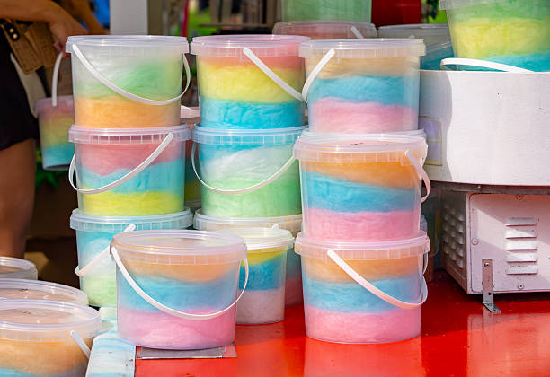 istock Colorful cotton candy packed in transparent plastic buckets, displayed on a market stall. A popular sweet treat often sold at fairs and outdoor events. 2218410077