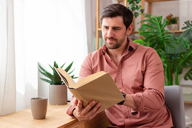 istock Focused man reading a book in a cozy home setting 2218410184