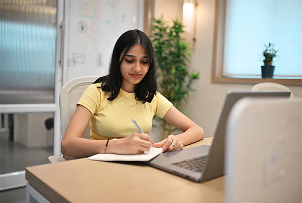 istock Focused young woman working on notes at modern office desk 2218411117