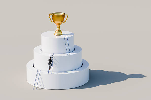 istock Man climbing ladders leaning against concentric cylinders up to golden trophy as the final goal. Career, competition, corporate ladder concept 2218417524