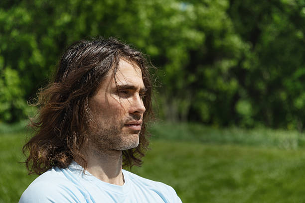 istock Thoughtful handsome brunette man with long hair in nature 2218419674