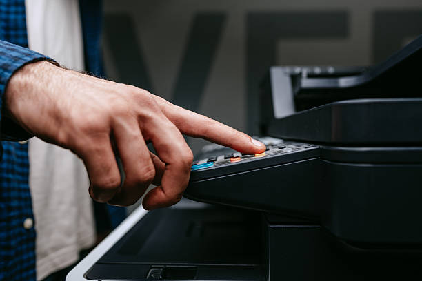 istock Person uses a multifunction printer to operate photocopying or scanning functions in an office setting during daylight hours 2218420091