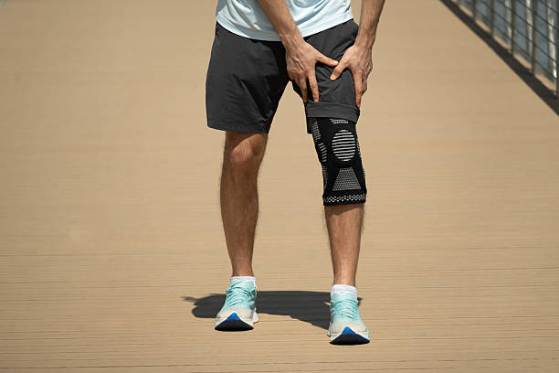 istock Athlete Holding Injured Knee in Supportive Brace 2218420898