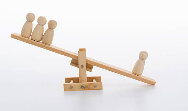istock Human figures on wooden seesaw 2218422888