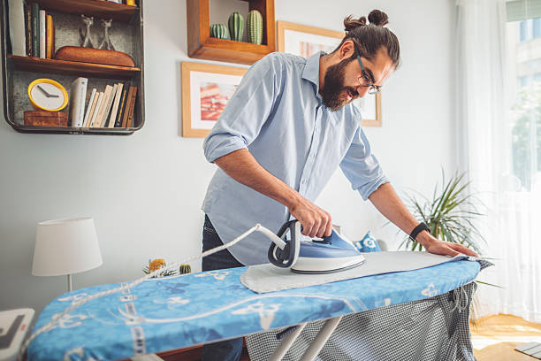 istock Young man ironing his shirt 2218423712