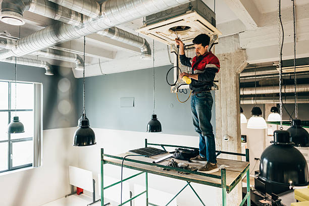 istock Worker installs ventilation system in modern commercial space during daylight hours 2218423983