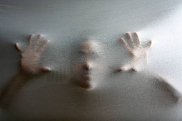 Person screaming in spooky situation behind fabric representing mental illness