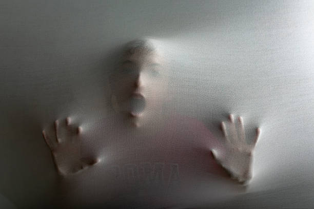 Person screaming in spooky situation behind fabric representing mental illness