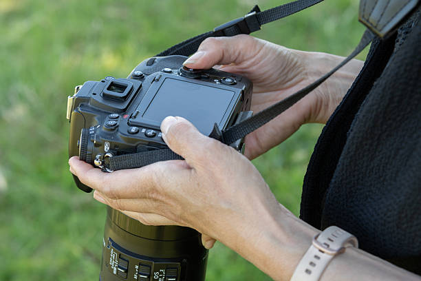 istock Female photographer adjusting camera settings outside 2218426554