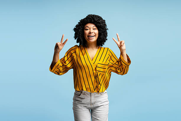 istock Young woman showing peace sign with both hands and smiling at camera 2218426962