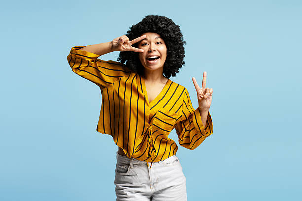istock Young woman showing peace sign with both hands and smiling at camera 2218426967