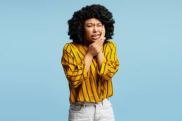 istock Young woman suffering from toothache touching cheek with painful expression 2218427038