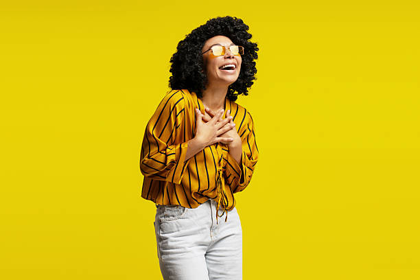 istock Young woman laughing with hands on chest on yellow background 2218427149