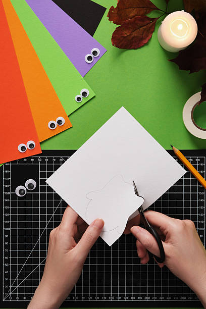 istock How to make a simple ghost craft. An idea for hobbies and creativity. Cut out the drawn silhouette with scissors. 2218428926