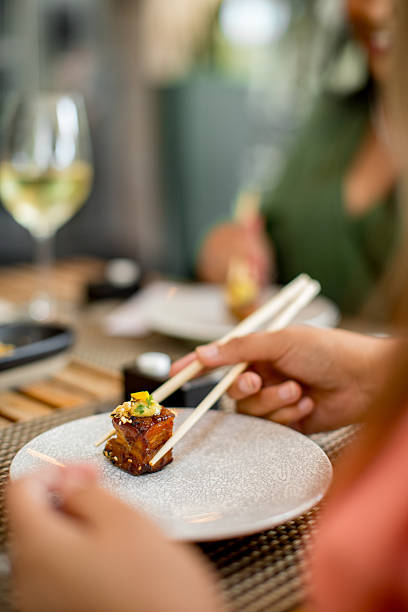 Female friends sharing a sushi platter in a restaurant using chopsticks