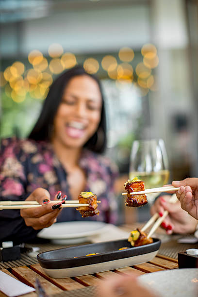 istock Female friends sharing a sushi platter in a restaurant using chopsticks 2218431077