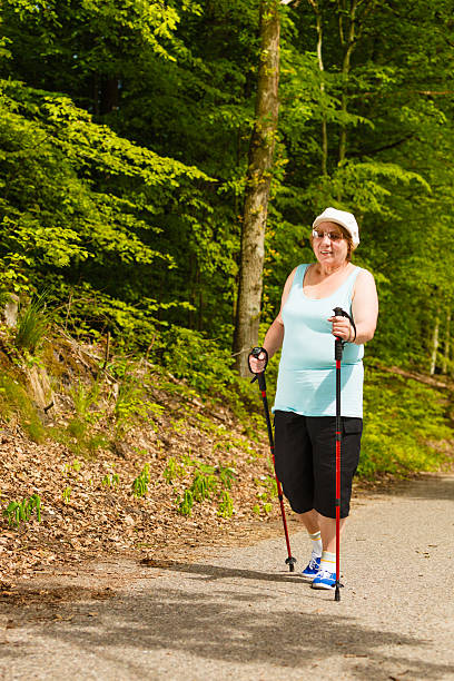 istock Senior woman practicing nordic walking in park 2218433178