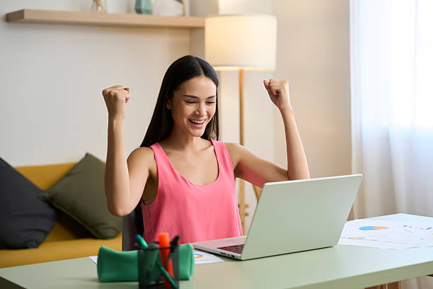 istock Young woman celebrating success while working remotely from home 2218434794