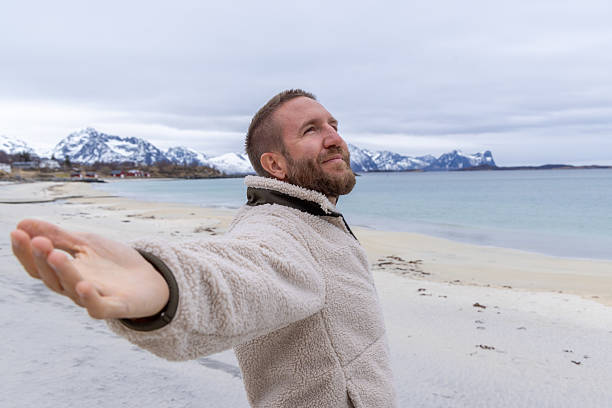 istock Man Enjoying Peaceful Beach with Mountain View, Arms Wide Open 2218435652
