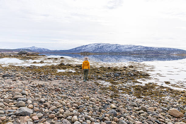 istock Hiker in Yellow Jacket Walking on Rocky Shoreline 2218436205
