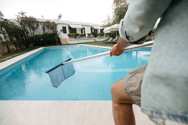 istock Young man using pool skimmer to clean backyard swimming pool 2218437119