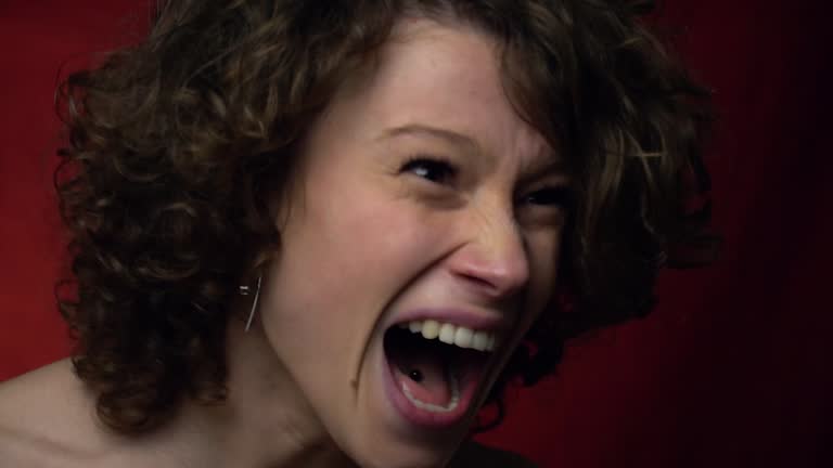 The face of an angry girl that screams and then smiles, slow motion