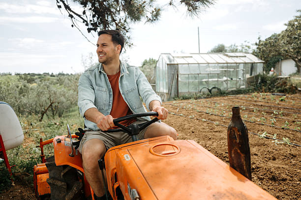 A portrait of a senior farmer sitting on his old tractor and smiling to the camera.