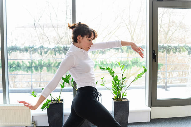 istock Woman in graceful dance stretch pose near panoramic window. 2218439356