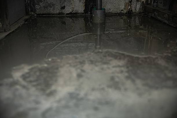 Fresh concrete floor leveling during home renovation Свежезалитый бетонный пол в помещении. Процесс выравнивания стяжки при ремонте дома или строительстве. Концепция строительства, отделки и укладки полов. Sump Pump and Basement Flood stock .