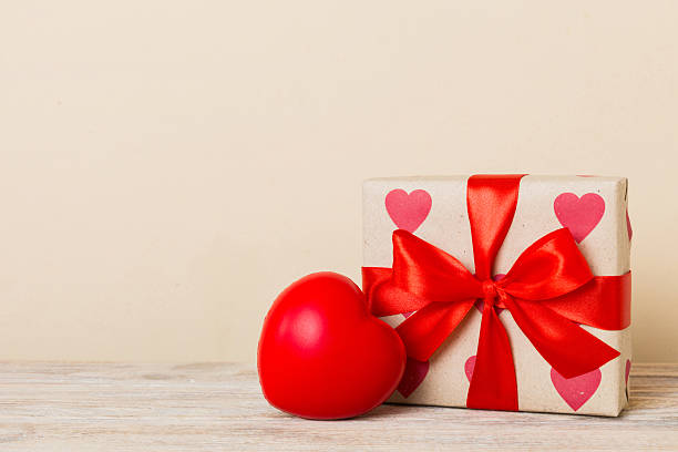 istock gift box with red bow and red heart on colored background. Perspective view. Flat lay 2218440225