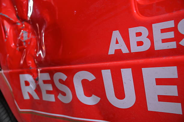 Firefighter in full protective gear sits on the step of a bright red fire truck, holding his white safety helmet with a downcast posture that conveys exhaustion and sadness. The scene reflects the emotional burden and mental toll firefighters may face after an unsuccessful emergency operation. It highlights themes of resilience, fatigue, and the challenging psychological impact of life-saving work and failure in high-stress situations.