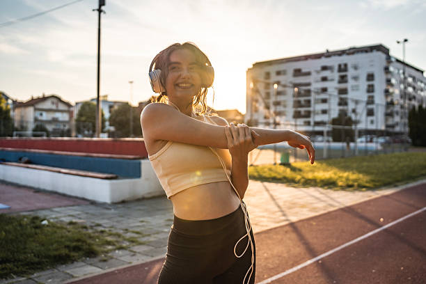 istock Young Woman Stretching Outdoors with Headphones During Sunset 2218443080