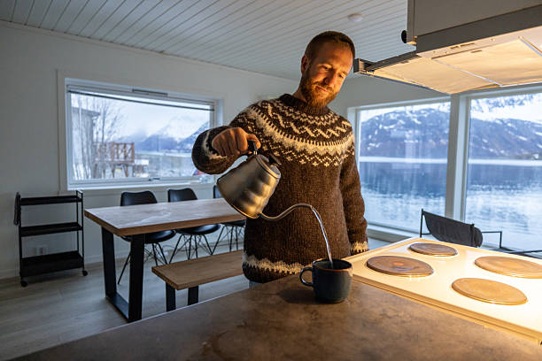 Man in Norwegian cottage preparing tea in the evening, sea and Mountain View
