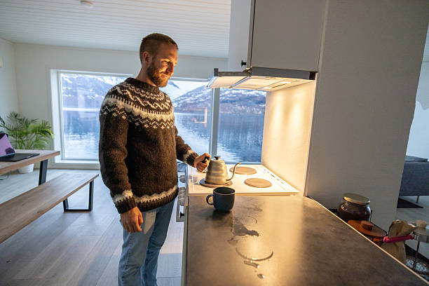 Man in Norwegian cottage preparing tea in the evening, sea and Mountain View