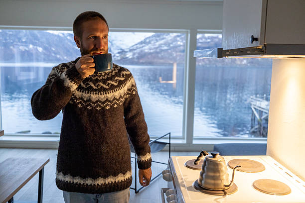 Man in Norwegian cottage preparing tea in the evening, sea and Mountain View